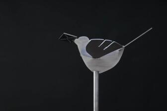 Edelstahl Vogel auf einer Stange und mit einem Brief im Schnabel