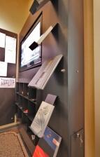 Monitorwand mit integriertem Prospekthalter und Regalfächern aus Stahl für das Helmut Kohl Haus in Hildesheim
