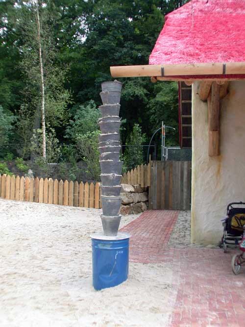 Gestapelte Eimer entwässern eine Dachrinne aus Holz