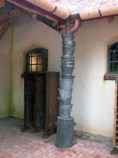 Gestapelte Eimer entwässern eine Dachrinne aus Holz