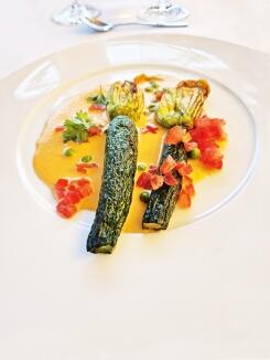 Gefüllte Zucchiniblüten mit Ricotta und Parmesan auf einem Tomatenspiegel