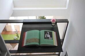 Buchablage mit integrierter Blumenvase aus 3mm lackiertem Stahlblech an einem Geländer