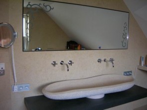 Badezimmer mit handgemeißeltem Waschbecken und einem hinterleuchteten Spiegel
