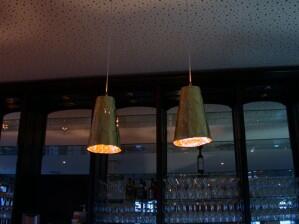Abgependelte Leuchten aus vergoldeter Kupferfolie für den Brasseriebereich im Kalimera