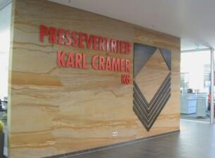 Wandgestaltung mit einem Logo aus Metall für den Pressevertrieb Karl Crämer KG