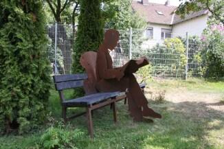 Bank mit rostiger Skulptur in Lebensgröße
