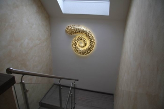 dreidimensionale Spiralstruktur aus Stahlblech geschweißt, vergoldet und mit LED hinterleuchtet