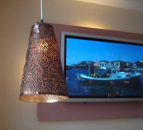 Abgependelte, gelochte Leuchten aus vergoldeter Kupferfolie für den Brasseriebereich in Kalimera