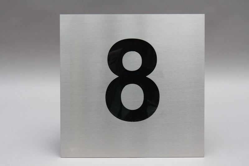 Hausnummer  "8 " aus Edelstahl mit schwarzem Acrylglas hinterlegt